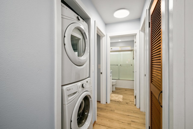 laundry area with stacked washer and dryer and light hardwood / wood-style floors