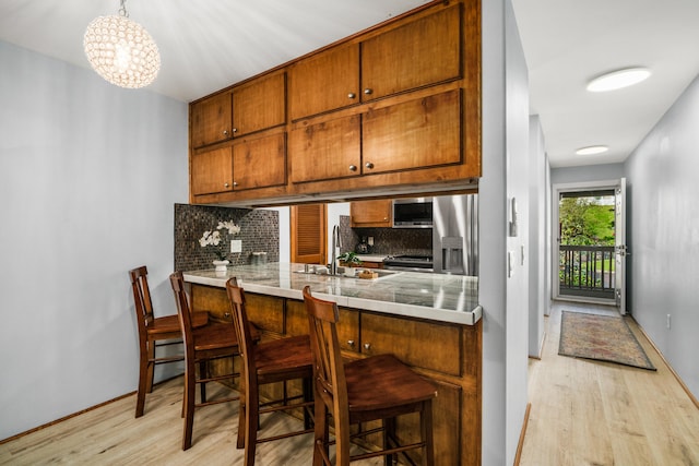 kitchen featuring a kitchen bar, kitchen peninsula, tasteful backsplash, hanging light fixtures, and sink