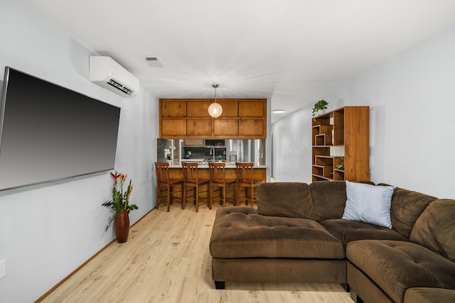 living room featuring an AC wall unit and light hardwood / wood-style floors