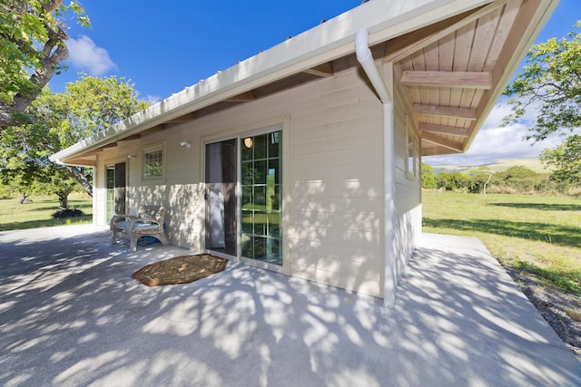 view of side of property featuring a lawn and a patio