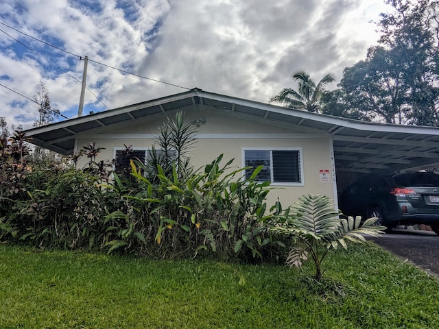 view of side of property featuring a carport and a yard