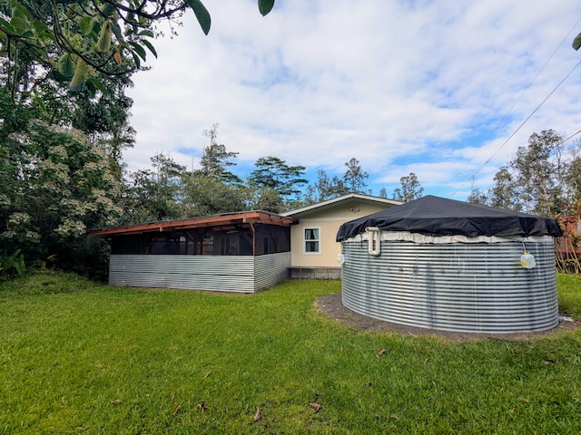 back of property featuring a swimming pool, a sunroom, and a lawn