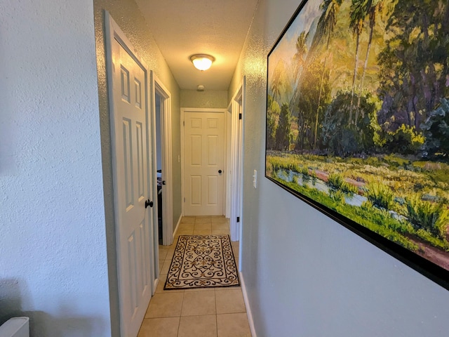 hall featuring a textured ceiling and light tile patterned floors