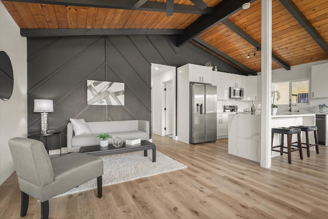 living room with lofted ceiling with beams, wood ceiling, ceiling fan, and light hardwood / wood-style floors