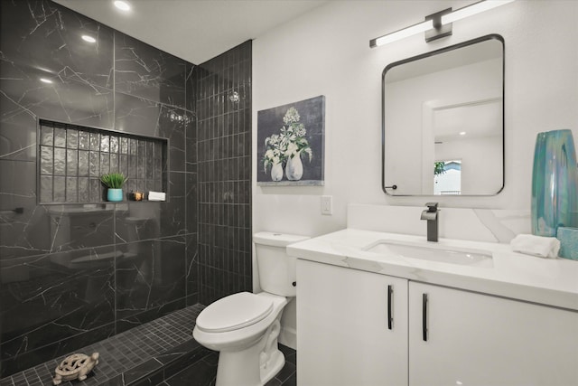 bathroom featuring vanity, tiled shower, and toilet