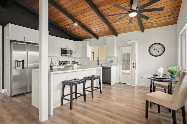 kitchen with appliances with stainless steel finishes, beamed ceiling, white cabinets, wooden ceiling, and light wood-type flooring