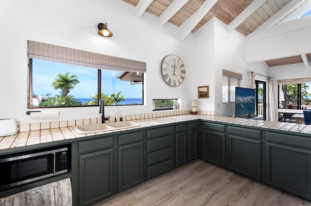 kitchen with sink, wood ceiling, tile countertops, and vaulted ceiling with beams