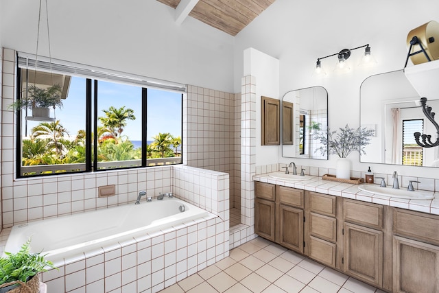 bathroom featuring tile patterned floors, vaulted ceiling, vanity, and tiled tub