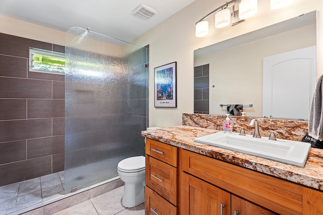 bathroom featuring vanity, a tile shower, tile patterned floors, and toilet