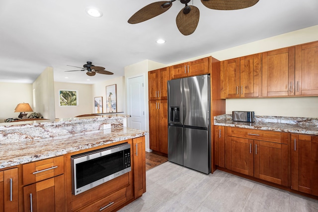 kitchen featuring light stone counters, ceiling fan, and appliances with stainless steel finishes