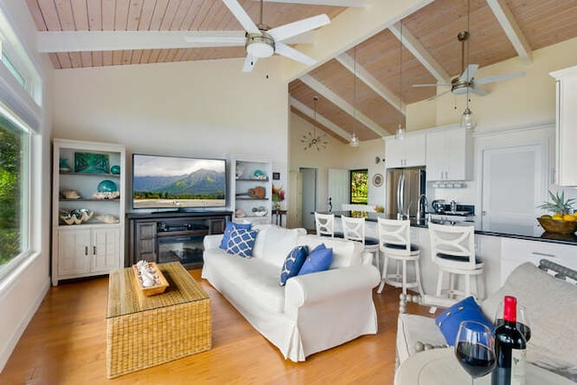 living room with beam ceiling, high vaulted ceiling, ceiling fan, and a wealth of natural light