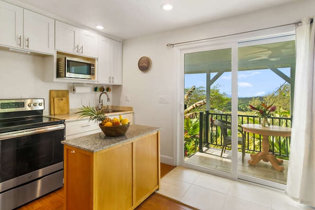 kitchen featuring appliances with stainless steel finishes, white cabinetry, sink, light stone counters, and light tile patterned floors