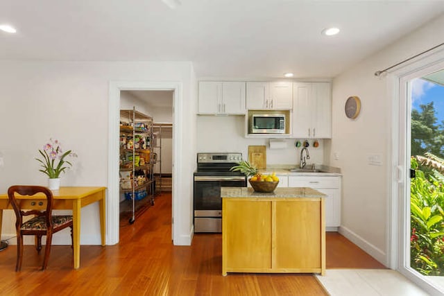 kitchen with sink, hardwood / wood-style floors, white cabinets, and stainless steel appliances