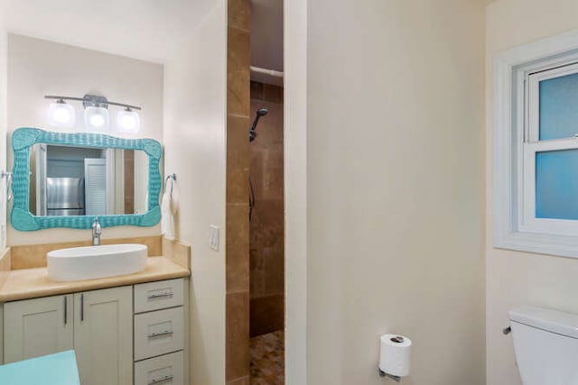 bathroom with vanity, toilet, and a tile shower