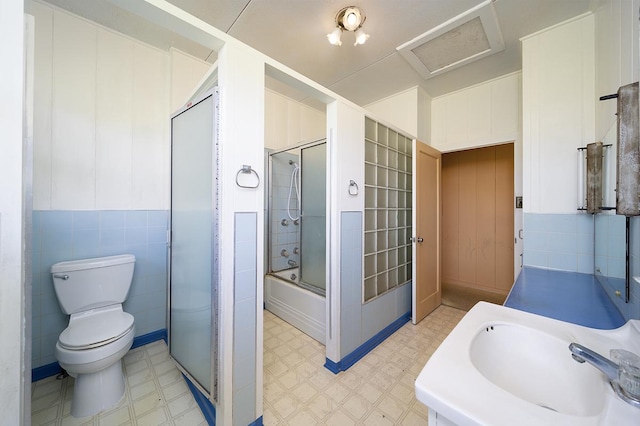 full bathroom with enclosed tub / shower combo, tile walls, vanity, and toilet