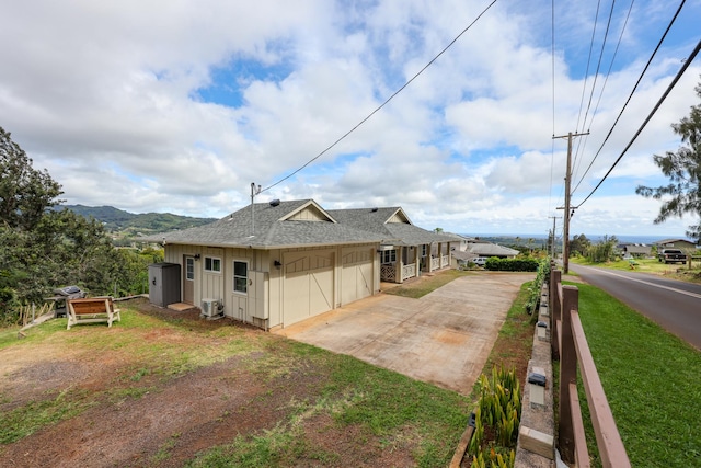 view of side of property with a garage, cooling unit, and a lawn