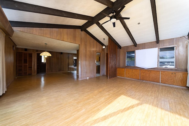 unfurnished living room with vaulted ceiling with beams, ceiling fan, wooden walls, and light wood-type flooring