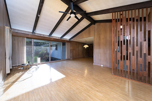 unfurnished living room with ceiling fan, lofted ceiling with beams, light hardwood / wood-style flooring, and wood walls