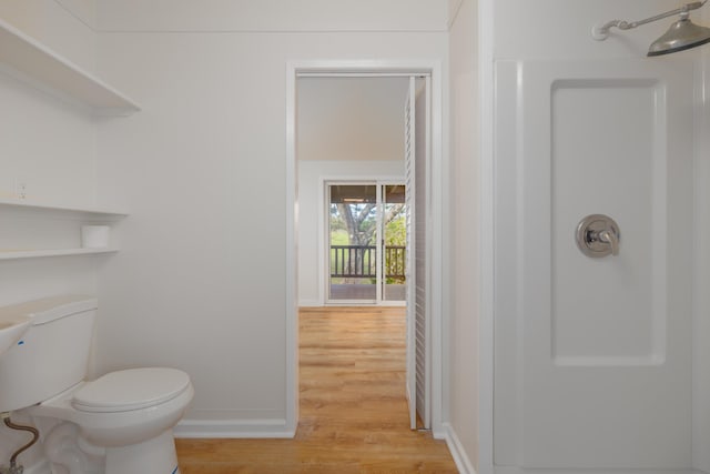 bathroom with hardwood / wood-style flooring, toilet, and walk in shower