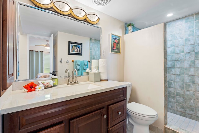 bathroom with vanity, ceiling fan, toilet, and a tile shower