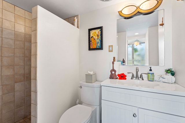 bathroom featuring vanity, a tile shower, ceiling fan, and toilet