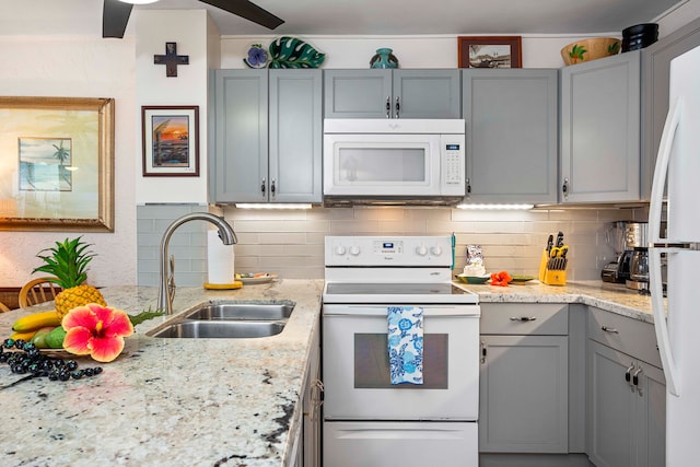 kitchen with sink, white appliances, gray cabinetry, backsplash, and light stone counters