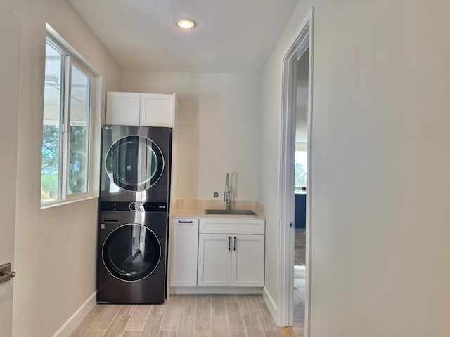 washroom with cabinets, stacked washer / drying machine, sink, and light hardwood / wood-style floors