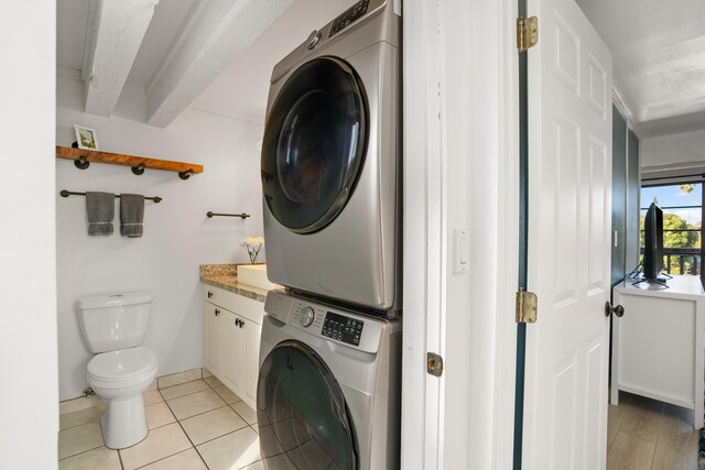 clothes washing area featuring light tile patterned floors, laundry area, and stacked washer and clothes dryer