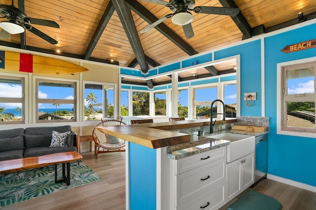 kitchen featuring light wood-style flooring, a sink, white cabinets, dark stone counters, and dishwasher