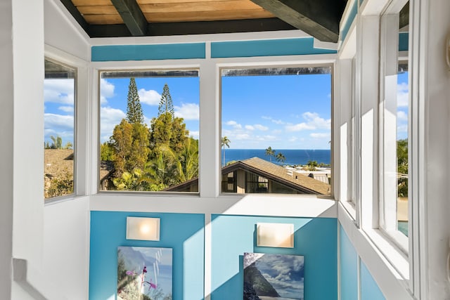 sunroom featuring beamed ceiling and a water view