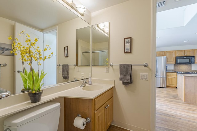 bathroom with wood-type flooring, a shower with door, vanity, decorative backsplash, and toilet