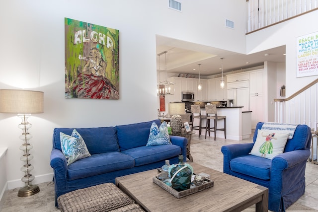 living room with an inviting chandelier and a towering ceiling