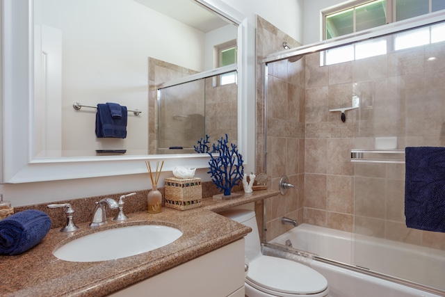 full bathroom with enclosed tub / shower combo, a wealth of natural light, vanity, and toilet