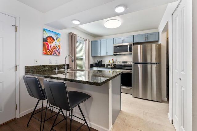 kitchen with sink, a kitchen breakfast bar, stainless steel appliances, blue cabinets, and kitchen peninsula