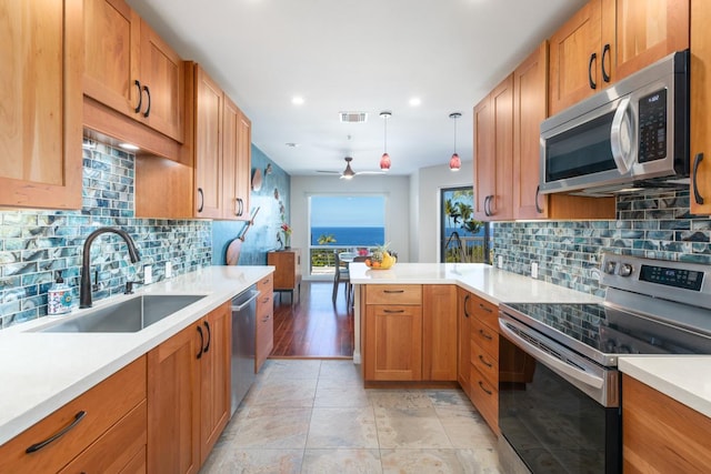 kitchen with sink, appliances with stainless steel finishes, hanging light fixtures, decorative backsplash, and kitchen peninsula