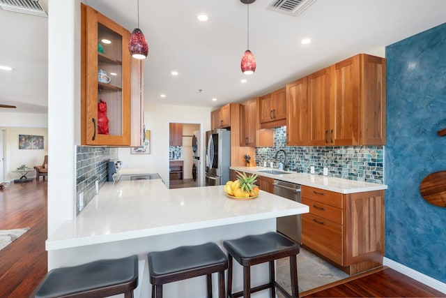 kitchen featuring a breakfast bar, sink, kitchen peninsula, pendant lighting, and stainless steel appliances