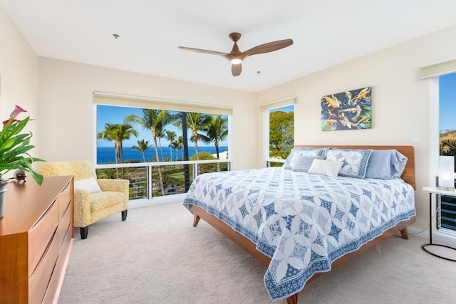 bedroom with a water view, light colored carpet, and ceiling fan