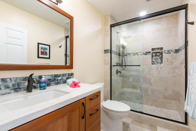 bathroom featuring a shower with door, vanity, and toilet