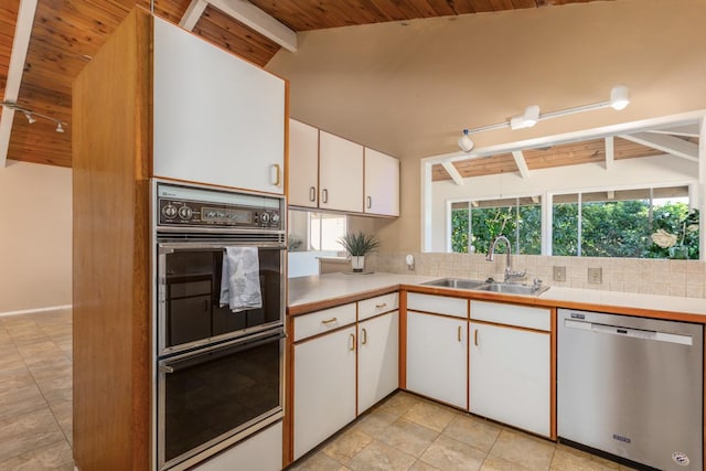 kitchen with lofted ceiling with beams, white cabinetry, sink, black double oven, and stainless steel dishwasher