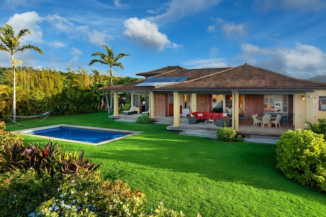 rear view of house featuring a yard, solar panels, and a swimming pool side deck