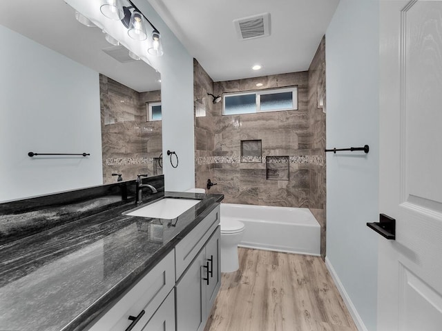 full bathroom featuring hardwood / wood-style flooring, toilet, vanity, and tiled shower / bath