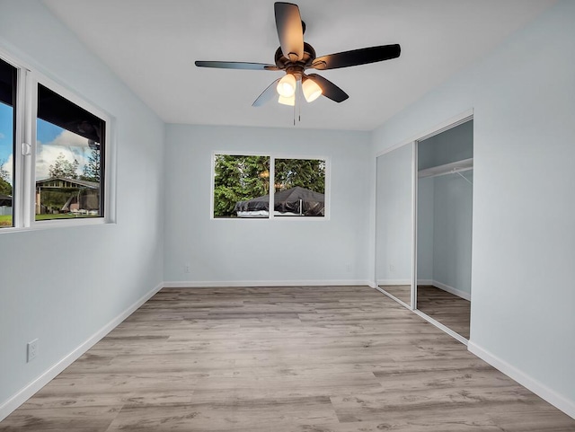 unfurnished bedroom with light hardwood / wood-style flooring, a closet, and ceiling fan