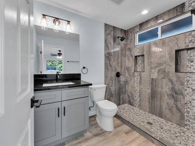 bathroom with vanity, toilet, hardwood / wood-style floors, and a tile shower