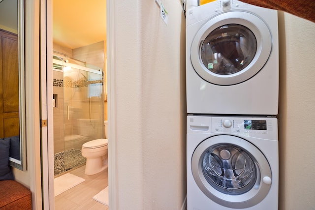 clothes washing area with hardwood / wood-style floors and stacked washer and dryer