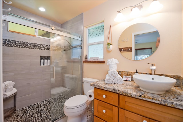 bathroom featuring vanity, toilet, and a shower with door