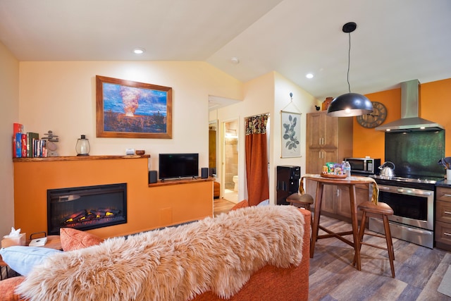 interior space with pendant lighting, vaulted ceiling, wall chimney exhaust hood, stainless steel range with electric stovetop, and dark hardwood / wood-style floors