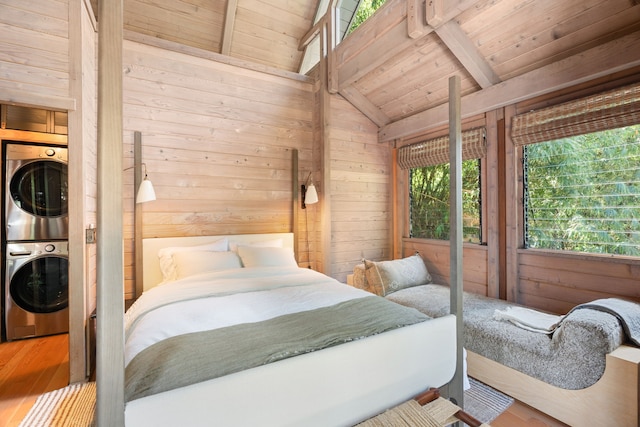 bedroom featuring stacked washer / dryer and wooden walls