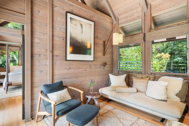 living area featuring light wood-type flooring, wood ceiling, plenty of natural light, and lofted ceiling with beams