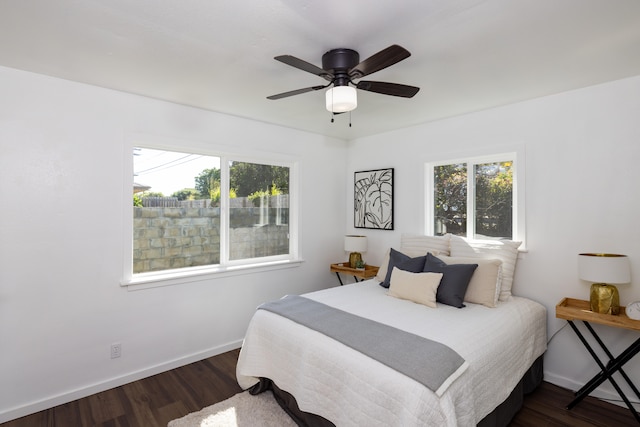 bedroom featuring ceiling fan, dark hardwood / wood-style floors, and multiple windows