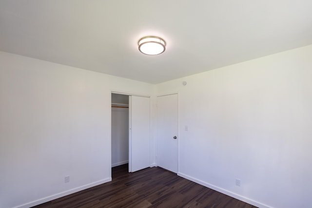 unfurnished bedroom featuring dark wood-type flooring and a closet